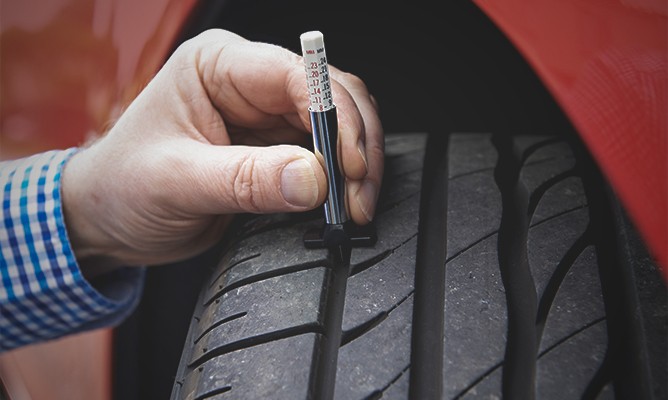 Inspecting-Car-Tires-With-Gauge
